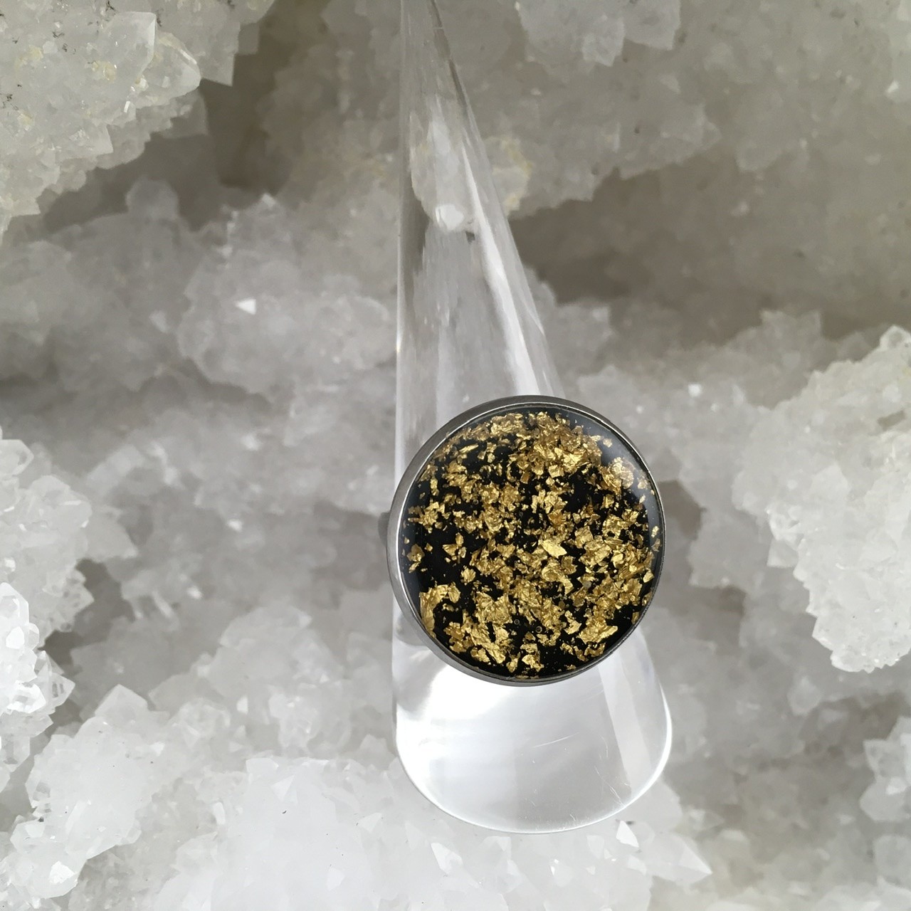 Bague en acier ronde résine et feuille d’or sur fond noir.